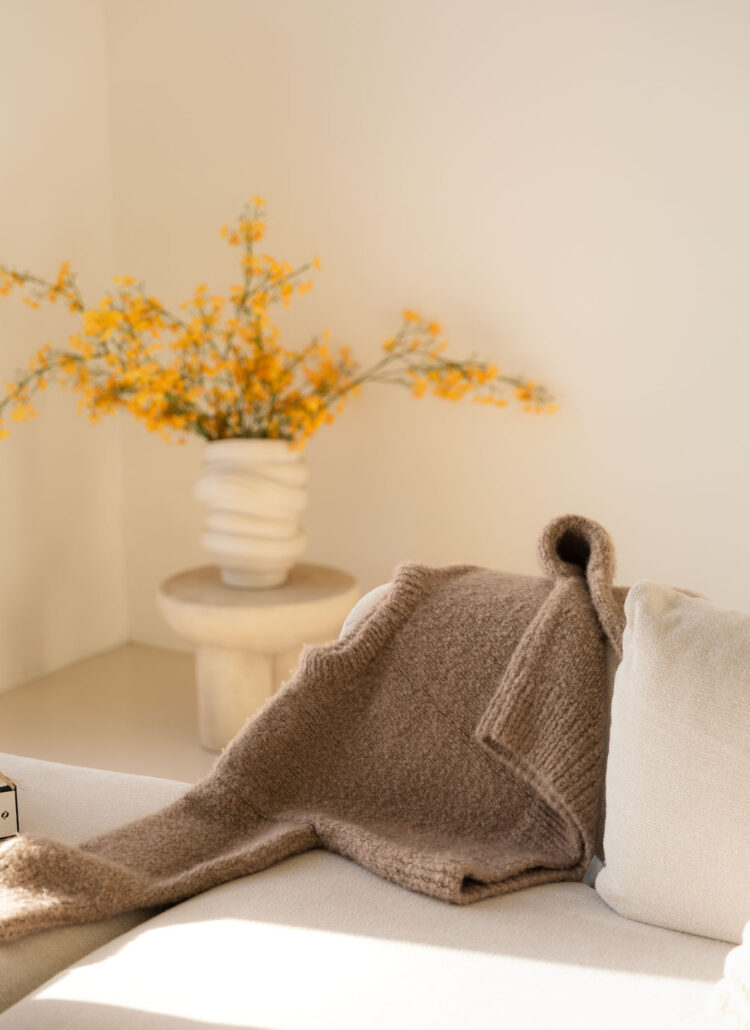 Beige Cashmere sweater resting on a white sofa